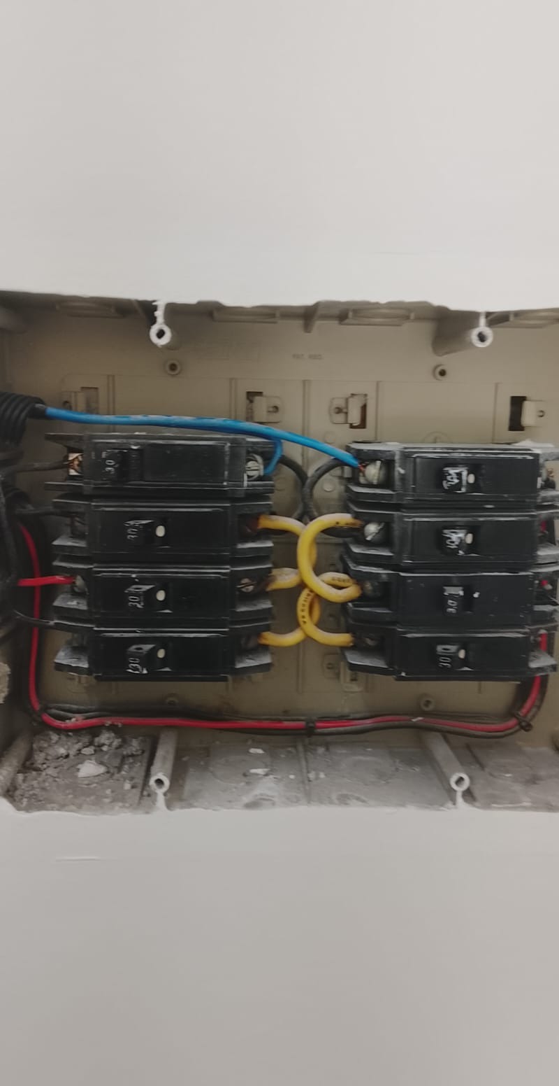 Quadro de distribuição com disjuntores e fiação organizada, evidenciando serviço de instalação ou manutenção elétrica residencial.