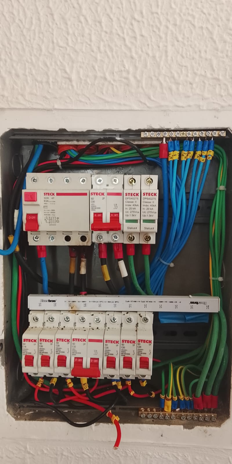 Quadro de distribuição elétrica residencial com disjuntores, IDR e DPS Steck instalados e fiação organizada por cores.
